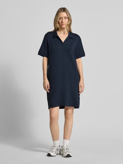 Frauenmodel trägt Regular Fit Polokleid mit Modal-Anteil von Marc O'Polo in Uni-Dunkelblau, Mini-Länge, Seitenschlitze, Stretch, Ganzkörperansicht von vorne.