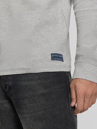 Männermodel trägt Regular Fit Longsleeve mit Waffel-Struktur von Scotch & Soda in Hellgrau, reine Baumwolle, Nahaufnahme Oberkörper.