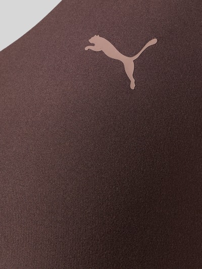 Frauenmodel trägt Slim Fit Sportbh mit Logo-Print Modell 'Cloudspun' von PUMA, braun, Elastischer-Material-Mix, Nahaufnahme Oberkörper.
