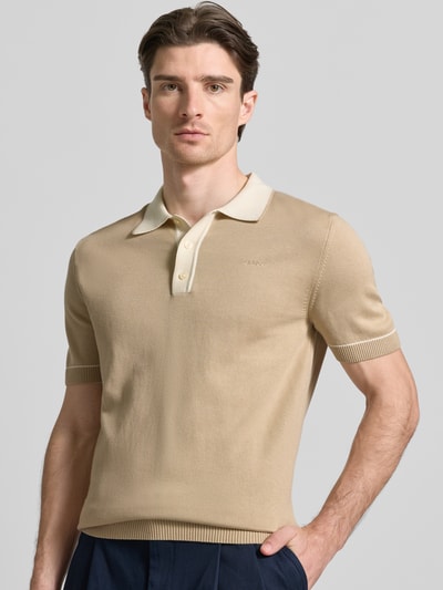 Männermodel trägt Slim Fit Poloshirt mit Logo-Stitching von Gant in Beige, Baumwoll-Modal-Mix, Polokragen, Nahaufnahme Oberkörper.