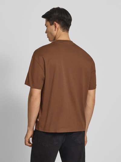 Männermodel draagt T-shirt met labelprint model 'TORREY' van Dickies van puur katoen in regular fit met ronde hals, ruglengte bij maat M 70 cm, geheel in effen bruin, structuur glad, Ganzkörperansicht Rückansicht.
