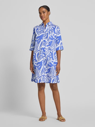 Frauenmodel trägt knielanges Hemdblusenkleid mit verdeckter Knopfleiste von Christian Berg Woman aus reiner Baumwolle im Straight Fit, Muster in Weiß und Blau, halblanger Arm, Hemdblusenkragen, glatte Textur, Ganzkörperansicht von vorne.