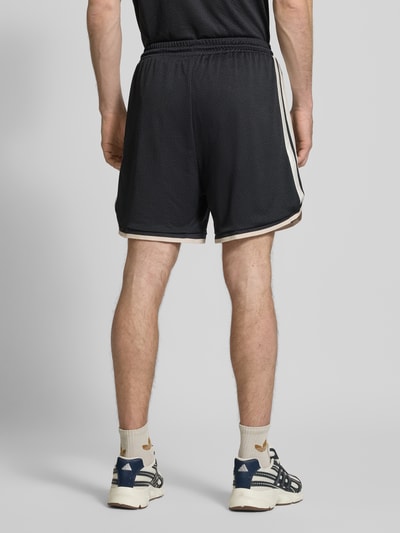Mężczyzna nosi Shorts mit elastischem Bund und Kordelzug od adidas Sportswear, luźny krój, logo z nadrukiem, czarne, Szerokość w rozmiarze M: 39 cm, długość nogawki wewnętrznej w rozmiarze M: 16 cm, widok całej sylwetki z tyłu.