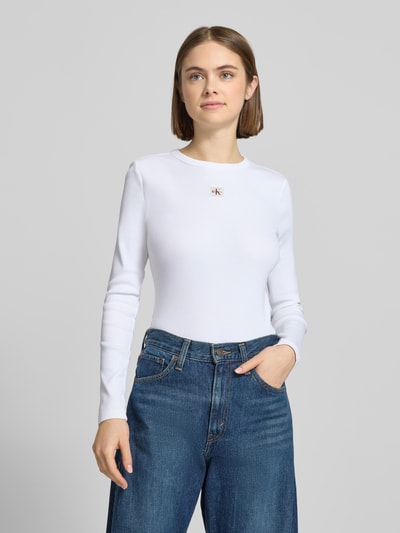 Vrouwenmodel draagt Longsleeve mit Label-Detail van Calvin Klein Jeans in wit, slim fit katoen-elastaanmix, ribboord, bovenlichaam close-up.