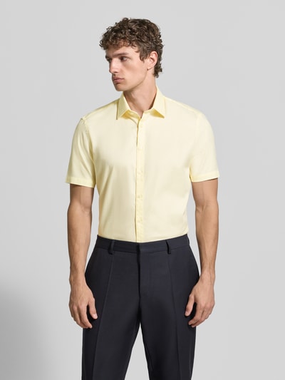 Männermodel trägt Slim Fit Business-Hemd aus Baumwolle mit Kentkragen von Jake*s, gelb, Knopfleiste, Ganzkörperansicht von vorne.
