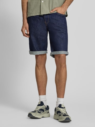 Männermodel trägt Regular Fit Jeansshorts aus Baumwoll-Mix von Tommy Jeans in dunkler Denim-Optik mit Label-Patch, 5-Pocket-Design, Nahaufnahme Unterkörper.