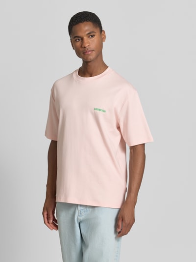 Männermodel trägt Oversized T-Shirt mit Label-Print von Lindbergh in Hellrosa aus Reine Baumwolle mit Rundhalsausschnitt, Rückenlänge bei Größe M 70 cm, Ganzkörperansicht von vorne.