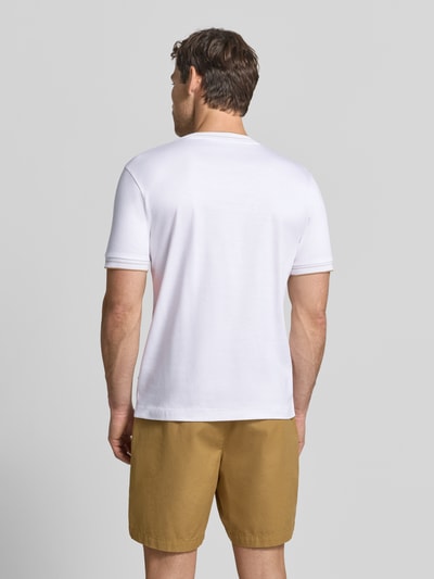 Męski model nosi białą koszulkę Slim Fit T-Shirt aus reiner Baumwolle Modell 'Tessler 195' von BOSS, brązowe szorty, gładka tekstura, Ganzkörperansicht Rückansicht