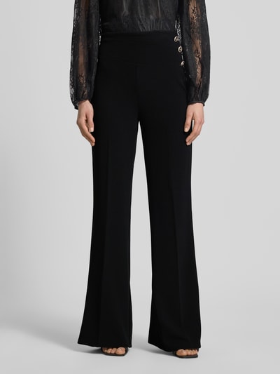 Frauenmodel trägt Flared Cut Hose mit Knöpfen von Rinascimento, schwarz, Material-Mix mit Stretch, Nahaufnahme Oberkörper bis Fuß.