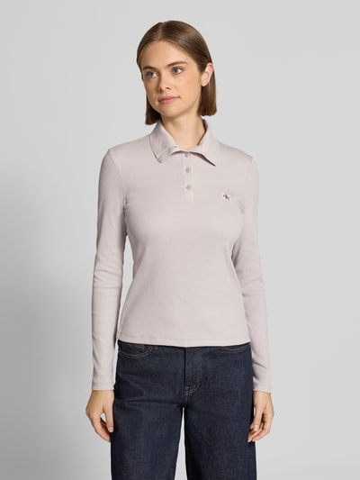 Frauenmodel trägt Slim Fit Langarmshirt aus Baumwoll-Mix von Calvin Klein Jeans in hellem Grau, glatte Textur, Ganzkörperansicht von vorne. Damen Langarmshirt von Calvin Klein Jeans.