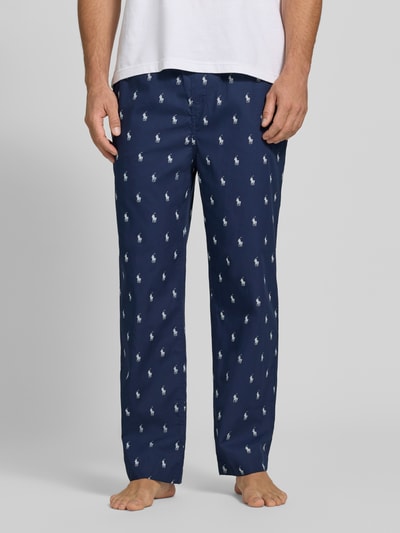 Männermodel trägt dunkelblaue Regular Fit Pyjama-Hose aus reiner Baumwolle von Polo Ralph Lauren Underwear mit Allover-Logo, Nahaufnahme Unterkörper.