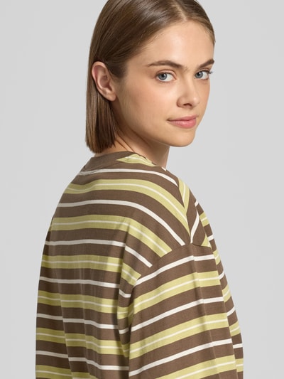 Vrouwenmodel draagt Relaxed Fit Langarmshirt uit puur katoen van Gina Tricot, gestreept in bruin en geel, detailopname bovenlichaam. Ruglengte bij maat S: 62 cm.