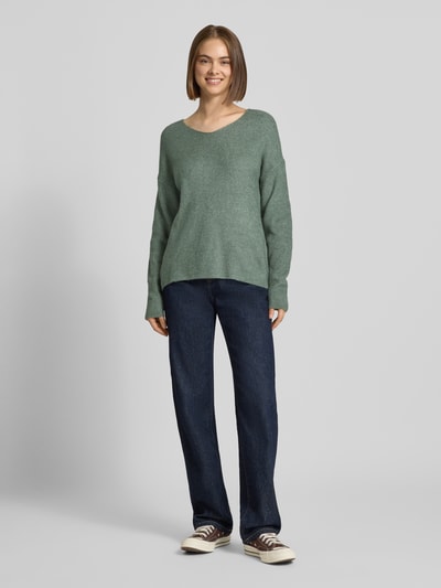 Frauenmodel trägt Regular Fit Pullover mit V-Ausschnitt Modell 'CAMILLA' von ONLY, Damen Pullover in Salbeigrün, Ganzkörperansicht von vorne.