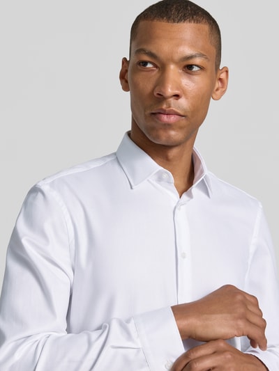 Männermodel trägt Super Slim Fit Business-Hemd mit Kentkragen von Jake*s aus Reine Baumwolle in Weiß, feine Textur, Nahaufnahme Oberkörper. Rückenlänge 79 cm, Schulterbreite 46 cm, Ärmellänge 66 cm, Knopfleiste, Sportmanschetten, abgerundeter Saum, Größe 39/40.