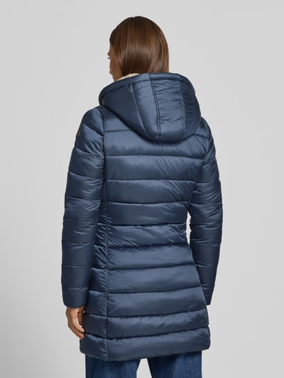 Frauenmodel trägt Steppmantel mit abnehmbarer Kapuze Modell 'CLELIA' von Save The Duck in Dunkelblau mit Stehkragen, Rückenansicht. Gerader Schnitt, Zweiwege-Reißverschluss, Label-Patch, seitliche Reißverschlusstaschen, leichte Steppstruktur, glatte Oberfläche. Rückenlänge 82 cm, Schulterbreite 39 cm, Brustweite 42 cm, Ärmellänge 65 cm.