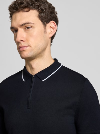 Męski model nosi Regular Fit Poloshirt mit Baumwoll-Anteil od HECHTER PARIS, ciemny kolor, elastyczna mieszanka bawełny, krój regular fit, kołnierzyk polo z zamkiem błyskawicznym, elastyczne zakończenia rękawów, długość tyłu w rozmiarze M 69 cm, zbliżenie na górną część ciała z przodu.