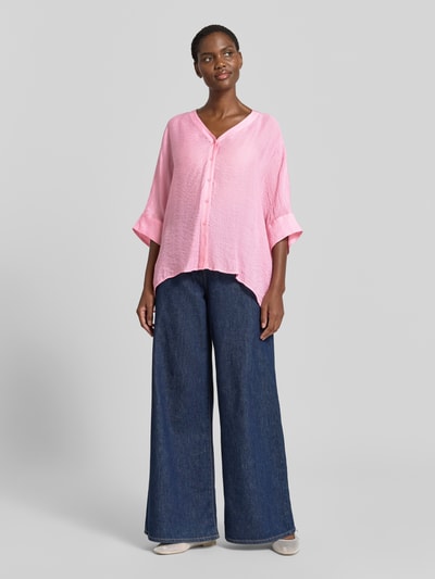 Frauenmodel trägt Relaxed Fit Bluse aus Viskose-Mix mit 3/4-Arm von Comma, rosa, strukturierte Textur, Knopfleiste, V-Ausschnitt, Ganzkörperansicht von vorne. Rückenlänge bei Größe S: 62 cm, Ärmellänge: 18 cm.