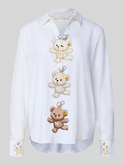Frauenmodel trägt Bluse aus Seiden-Mix mit Motiv-Print von HERZENS, krój loose fit, kołnierzyk koszulowy, dekolt w serek, nadruk z motywem, dłuższy tył, zaokrąglony dół, długość tyłu 69 cm, długość rękawów 60 cm, mieszanka jedwabiu z dodatkiem streczu, widoczne jasne i beżowe kolory oraz wyraźna tekstura, Ganzkörperansicht von vorne.