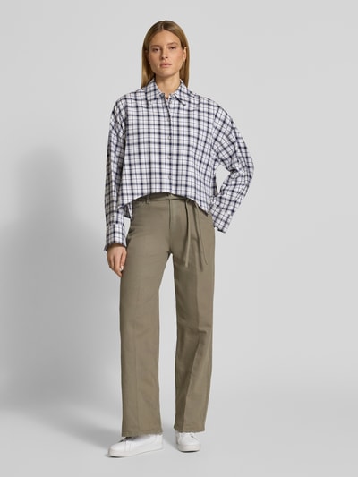 Modelka kobieca nosi Wide Fit Jeans mit Bügelfalten od Christian Berg Woman, beżowy kolor, elastyczny bawełniany materiał, krój wide fit, prasowane kanty, odpinany pasek materiałowy, pięć kieszeni, zapięcie na guzik i zamek, szerokość w rozmiarze 36/32: 107 cm, długość wewnętrzna nogawki: 77 cm, pełny widok sylwetki z przodu.
