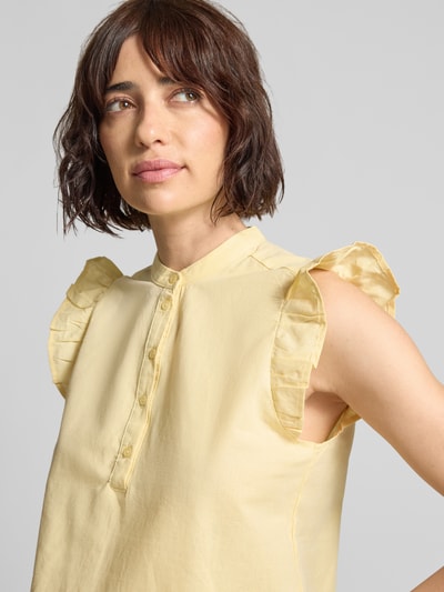 Modelka kobieca nosi Regular Fit Bluse aus Baumwoll-Leinen-Mix Modell 'SELMA' von Vero Moda, efekt: jednolity kolor, krój regular fit, stójka, wysokie zapięcie, listwa guzikowa, zakończenie rękawów: frill, wykończenie materiału: popelina, mieszanka bawełny i lnu, jasny żółty, gładka tekstura, prosty fason, widoczne detale przy ramionach, Nahaufnahme górnej części ciała.