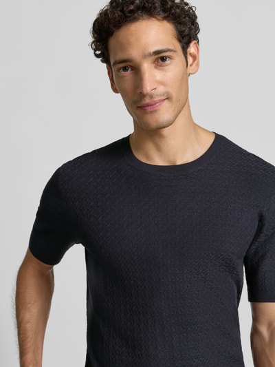 Männermodel trägt T-Shirt aus Viskose-Mix in Strick-Optik von Emporio Armani, Schwarz, schmale Passform, Nahaufnahme Oberkörper.
