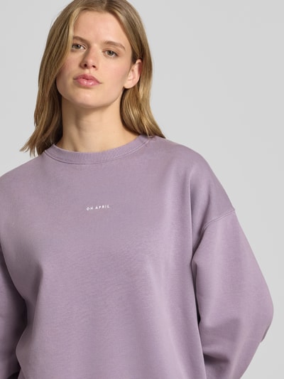 Frauenmodel trägt Oversized Sweatshirt mit Rundhalsausschnitt und Logo von OH APRIL aus Baumwoll-Mix in Flieder, Nahaufnahme Oberkörper.