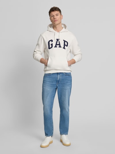 Mannenmodel draagt Hoodie met kangoeroezak van GAP, katoenmix, losse pasvorm, labelstitching, ribboorden, wit, voorkant, full body.