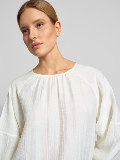 Modelka nosi blusenshirt mit raglanärmeln Modell 'Fibiza' od OPUS, mieszanka lyocellu, luźny krój, okrągły dekolt, kremowy kolor, tekstura lekko marszczona, zbliżenie na górną część ciała.