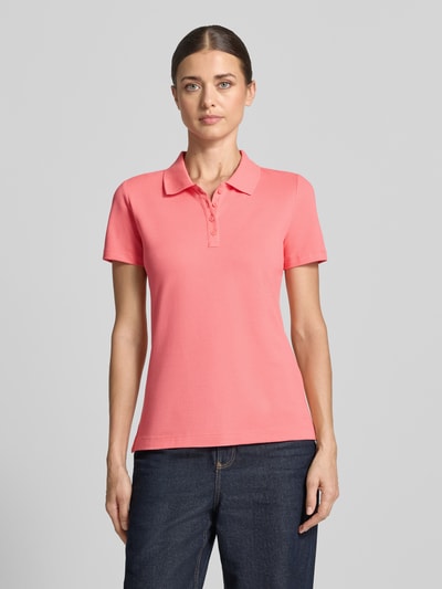 Frauenmodel trägt Regular Fit Poloshirt aus reiner Baumwolle von Tom Tailor in Koralle, glatter Stoff, schlichte Form, Ganzkörperansicht von vorne, Damen Poloshirt von Tom Tailor.