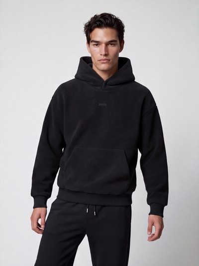 Männermodel trägt Regular Fit Sweatshirt mit Teddyfleece-Kapuze von BOSS, unifarben, mit Kängurutasche, Ganzkörperansicht von vorne.