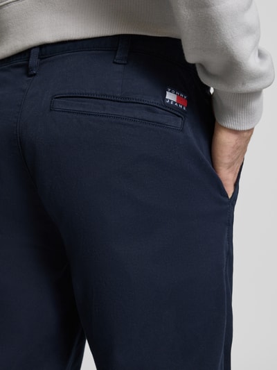 Männermodel trägt Tapered Chino aus Baumwoll-Mix Modell 'SONNY' von Tommy Jeans, Optik: Unifarben, Gesäßtasche, Detailaufnahme Rückansicht.