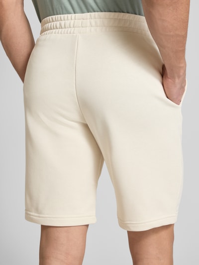 Männermodel trägt Shorts mit Label-Stitching von PUMA PERFORMANCE in Beige, Baumwoll-Mix, elastischer Bund, Ganzkörperansicht Rückansicht.