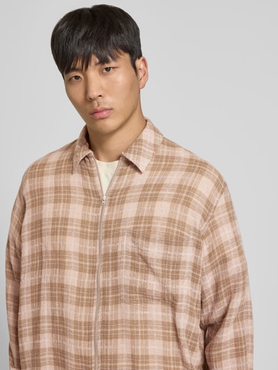 Männermodel trägt Freizeithemd aus Viskose-Mix von WON HUNDRED, kariertes Muster in Beige und Rosa, Reißverschluss, Nahaufnahme Oberkörper.