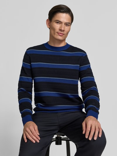 Männermodel trägt Strickpullover mit Struktur-Muster von Armani Exchange, reine Baumwolle, Blau-Schwarz, lockerer Schnitt, Nahaufnahme Oberkörper.