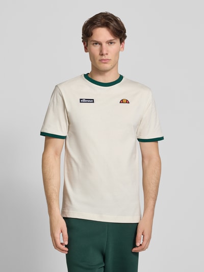 Męski model nosi t-shirt im Retro-Look model 'RINGETTO' od ellesse, bawełna, krój regular fit, wyhaftowane logo, okrągły dekolt, długość tyłu w rozmiarze M: 70 cm, kolory kremowy i zielony, widok całej sylwetki z przodu.
