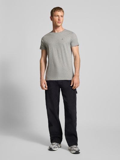 Męski model nosi T-shirt in Melange-Optik od Tommy Jeans, bawełna, prosty krój, efekt melanżu, okrągły dekolt, wyhaftowane logo, długość tyłu 68 cm, rozmiar M, całopostaciowy widok z przodu.