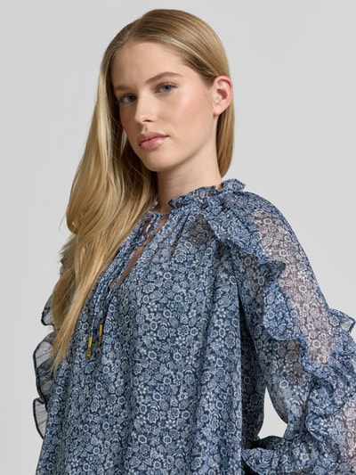 Vrouwenmodel draagt Blusenshirt met Rüschen und Serafino-Kragen van MICHAEL Michael Kors, semitransparant blauw patroon, elastische mouwboorden, ondertop, detailopname bovenlichaam.