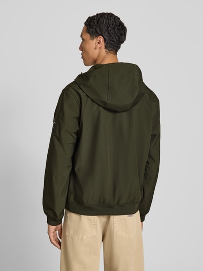 Männermodel trägt Regular Fit Jacke mit Logo-Detail von JACK & JONES in Dunkelgrün, Softshell mit Kapuze und elastischen Abschlüssen, Ganzkörperansicht Rückansicht.