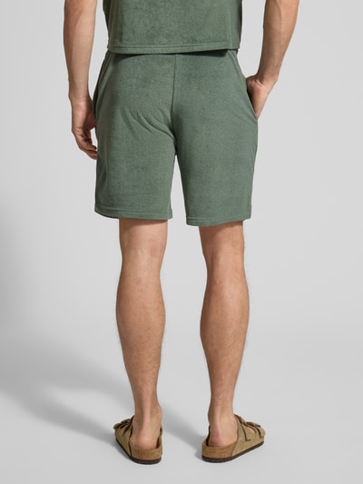 Männermodel trägt Shorts mit elastischem Bund von MCNEAL aus Baumwoll-Mix in Grün, Regular-Fit mit Tunnelzug, Ganzkörperansicht Rückansicht.