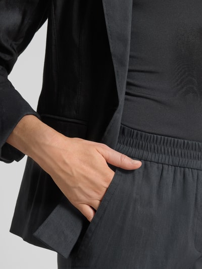 Vrouwenmodel draagt Straight Fit Leinenhose met Viskose-Anteil van Marc Cain in donkere tinten, elastische band, achterzak, detailopname rechterhand in zak.