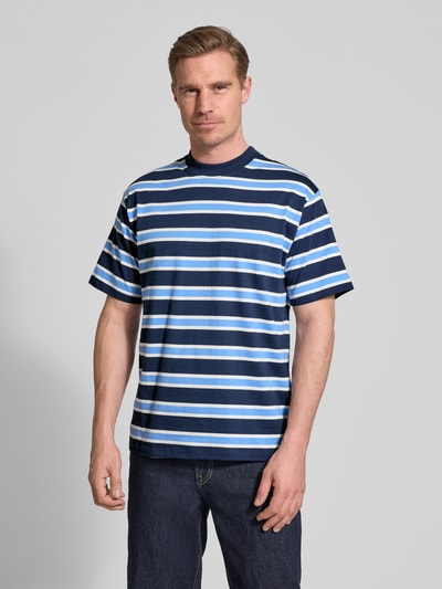Männermodel trägt Regular Fit T-Shirt mit Rundhalsausschnitt von Casual Friday aus reine Baumwolle, blau gestreift, Kurzärmelig, Ganzkörperansicht von vorne.