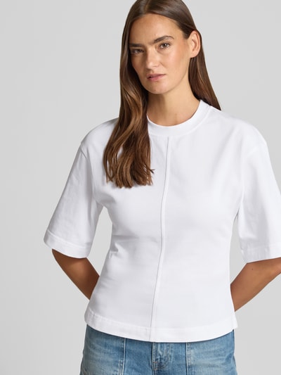 Frauenmodel trägt Damen T-Shirt mit 1/2-Arm Modell 'SADISAS' von Samsøe Samsøe aus Reine Baumwolle, Taillierter Schnitt, Rundhalsausschnitt, Rückenlänge 55 cm bei Größe S, weiße Farbe, glatte Textur, Nahaufnahme Oberkörper.