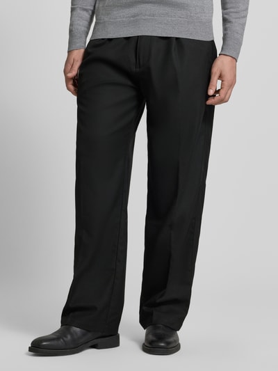Mannenmodel draagt Weite Hos mit Viskose-Anteil Modell 'RIKO261' van HUGO in effen zwart met label patch, regular fit, zijzakken, zicht op volledige voorkant, close-up bovenlichaam tot voeten.