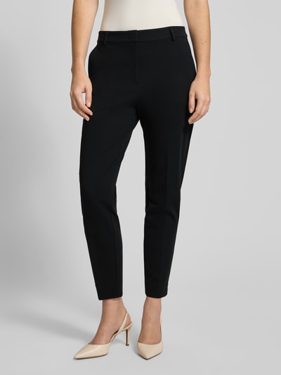 Frauenmodel trägt Stoffhose mit Gesäßtasche von Comma, schwarze Farbe, Viskose-Mix mit Stretch-Anteil, lockerer Schnitt, Bundfalten, französische Eingrifftaschen, Bundweite 38 cm, Innenbeinlänge 72 cm, Nahaufnahme Oberkörper.