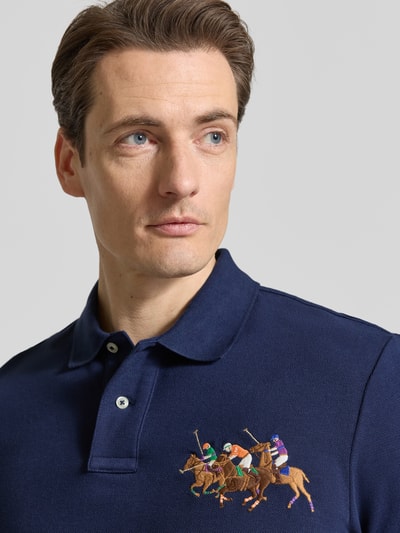 Männermodel trägt Regular Fit Poloshirt aus reiner katoen van Polo Ralph Lauren met effen look, motiefstitching, polokraag en piquéstructuur, kleur donkerblauw, detailopname bovenlichaam.
