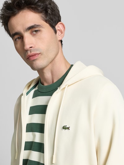 Männermodel trägt Regular Fit Sweatjacke aus Baumwoll-Mix von Lacoste, Optik: Unifarben, Logo-Stitching, Reißverschluss, Nahaufnahme Oberkörper.