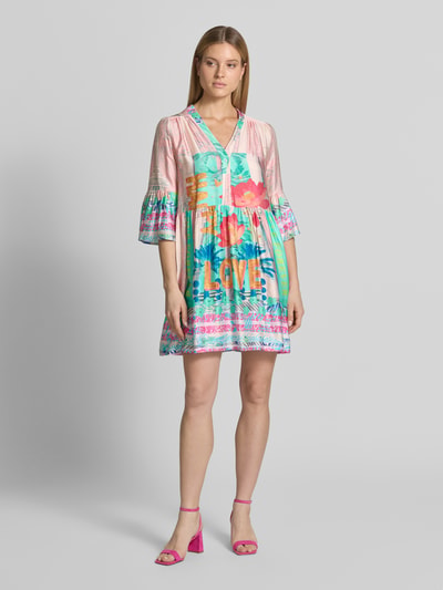 Kobiece modelka nosi sukienka mini z czystej wiskozy Relaxed Fit model 'Love' od miss goodlife, kwiatowy nadruk na całej powierzchni, rękaw o dł. 1/2, dekolt w serek, długość tyłu w rozmiarze S: 88 cm, szerokość w rozmiarze S: 50 cm, długość rękawów w rozmiarze S: 47 cm, kolorowe wzory, miękka tekstura, widok całej sylwetki z przodu.