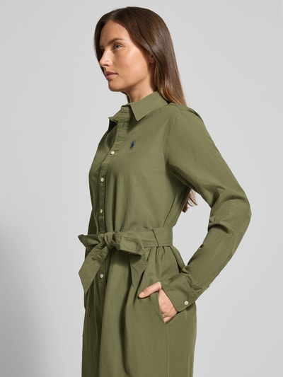 Kobiece model nosi sukienka midi z listwą guzikową Polo Ralph Lauren, mieszanka bawełny i lnu, taliowany krój, pasek w talii, kołnierzyk koszulowy, wyhaftowane logo, długość tyłu 112 cm, szerokość klatki piersiowej 52 cm, długość rękawów 63 cm, zdjęcie z boku, ujęcie od pasa w górę.