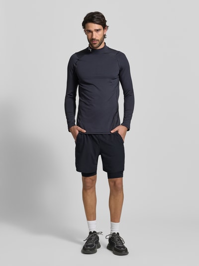 Männermodel trägt Regular Fit Shorts mit integrierten Tights Modell 'Vanish' von Under Armour, Schwarz, Logo-Print, Ganzkörperansicht von vorne.