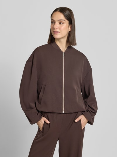 Modelka nosi Jacke mit Reißverschluss Modell 'Janica' od OPUS, brązowy kolor, materiał z domieszką wiskozy, krój regular fit, zamek, zdjęcie całej sylwetki z przodu, długość tyłu 55 cm, szerokość ramion 60 cm, szerokość w biuście 65 cm, długość rękawa 61 cm w rozmiarze 36.
